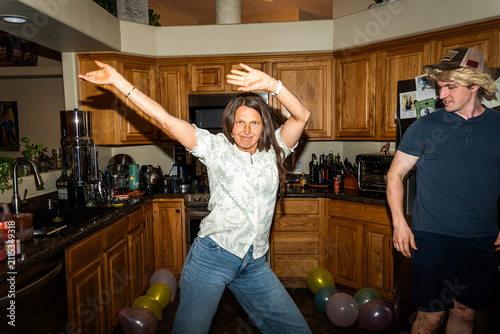 Canvastavla Woman dancing with raised arms in bright kitchen during playful home party