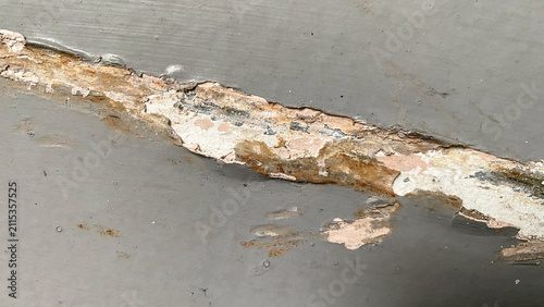 Gray plaster wall with visible cracks and shadow patterns, illustrating structural aging and surface deterioration.