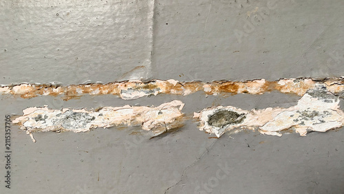Gray plaster wall with visible cracks and shadow patterns, illustrating structural aging and surface deterioration.