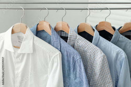Quadro su tela A row of blue-toned casual shirts hanging on wooden hangers on a folding clothes drying rack