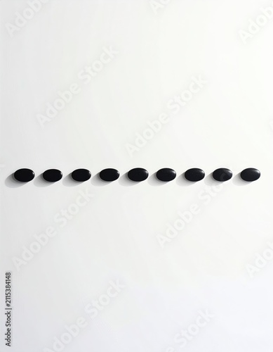 A horizontal line of nine glossy black oval shapes on a stark white background