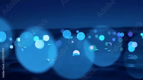 Abstract glowing blue bokeh lights on dark water surface
