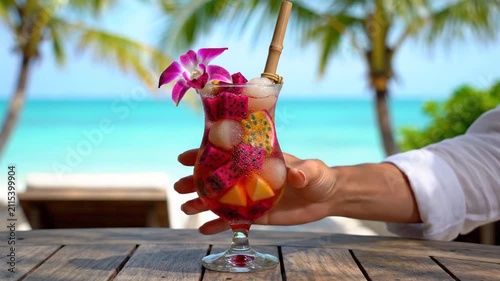 Exotic tropical fruit cocktail on wooden table at sunny beach