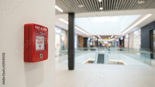 Fire alarm pull station mounted on a wall in a modern shopping mall