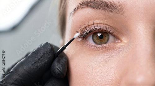 Closeup of a professional lash lift procedure being performed on a womans eye by a technician wearing black gloves