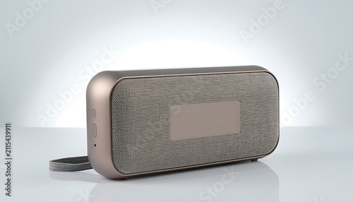 Modern portable wireless speaker with metallic finish and fabric mesh on studio background for elegant audio experience