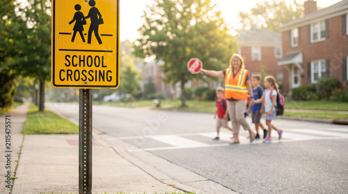 Crossing guard helping school children cross the street safely in a residential neighborhood during the morning commute to school