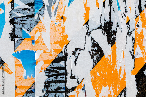 Torn and ripped colorful paper posters on urban street wall