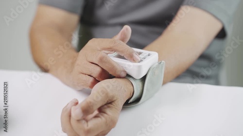 Close up of a senior using a digital wrist blood pressure monitor to check blood pressure at home, representing hypertension management, cardiovascular health, home care, medical monitoring, and welln