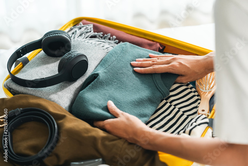 Happy Beautiful woman to folding her clothes pack suitcase for travel in holiday. Young female folding clothes while packing luggage at home.