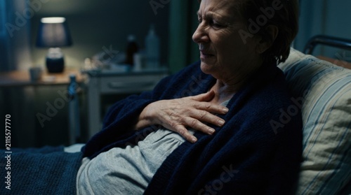 Elderly Woman Experiencing Chest Pain While Lying In Hospital Bed At Night