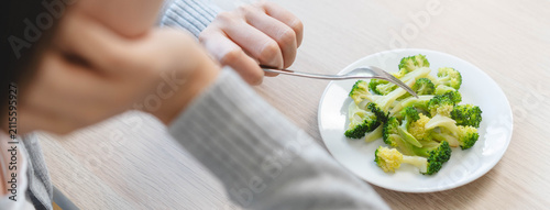 Принти на полотні Close up of a woman hand holding fork with green broccoli over a white plate for