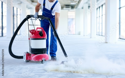 Professional Worker Vacuuming Dust from Floor in Empty Building Space