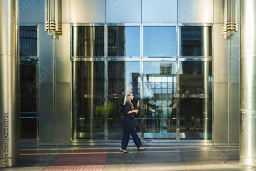 Fotografía Woman walking confidently outside a contemporary office building, reflecting cit
