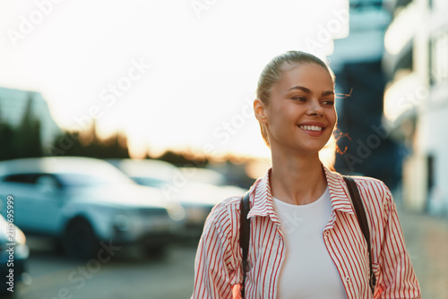Foto Cheerful woman outdoors, smiling in sunlight, wearing a casual striped shirt, ur
