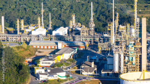 Aerial view of the petrochemical complex featuring industrial towers, pipelines, and storage tanks surrounded by lush forest in Santo Andre, State of Sao Paulo, Brazil.