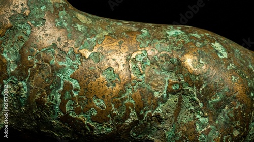 Macro view of weathered bronze surface featuring intense green oxidation and textured verdigris patina from aging