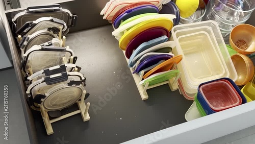 Colorful plastic containers and lids organized in a kitchen drawer, showcasing a neat arrangement with visible dividers and a clean, modern design aesthetic