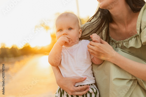 Mother holding her baby outdoors during a beautiful golden hour sunset