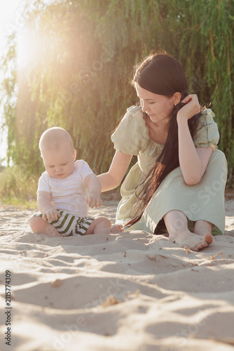 Mother and baby enjoying a sunny day together on a sandy beach with soft sunlight