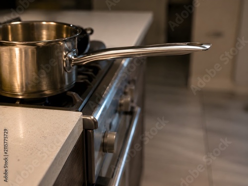 Cooking pot handle extending dangerously beyond edge of stove, kitchen fire risk prevention awareness scene