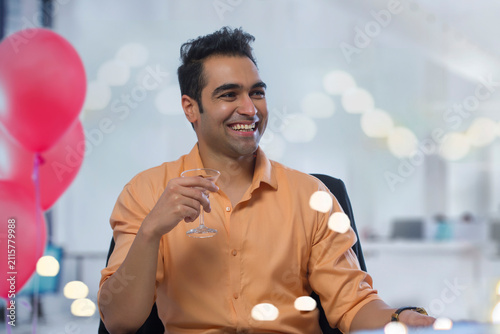 Young man having a drink at his office party.