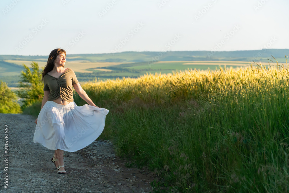 Obraz premium Happy Young Woman Dancing in White Skirt on Summer Path