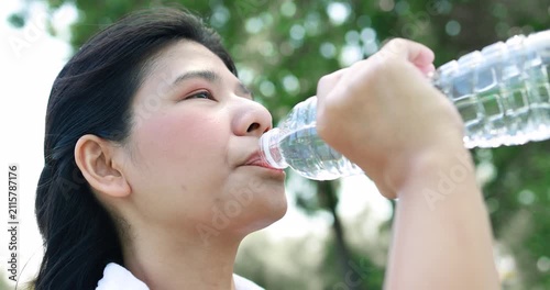 Young woman drinking bottled water outdoors on a sunny day, staying hydrated after activity. Healthy lifestyle, refreshment, wellness, summer, fitness, and self-care concept