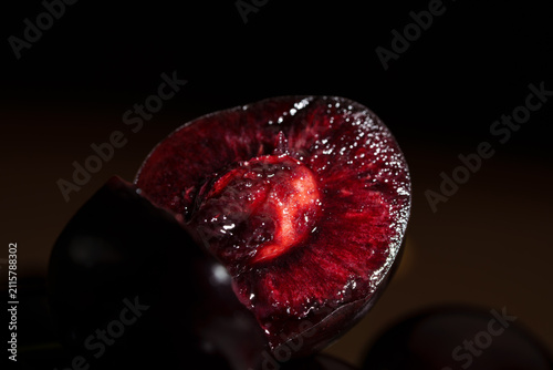 Konstfotografi Close-up of sliced dark red cherry with glossy juicy flesh, visible pit cavity,