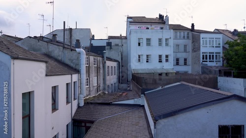 Detalle de un gato sobre los tejados de varias casas antiguas, observando desde lo alto el entorno de un barrio histórico.