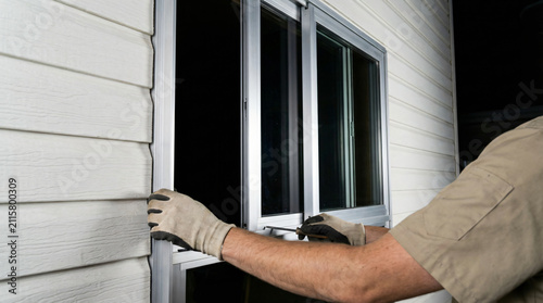 Man installing or repairing a window on the exterior of a house, focusing on home improvement and maintenance.