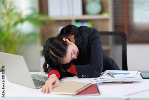 Fotografía Exhausted young businesswoman sleeping at office desk, suffering from burnout an