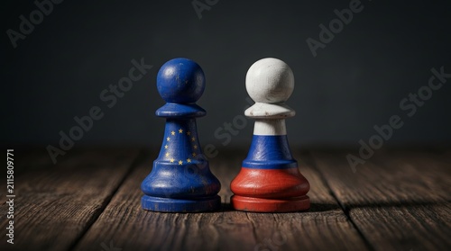Chess pawns decorated with Russian and European Union flags standing against each other.