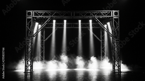 Stage truss structure with bright spotlight beams and haze on dark performance background