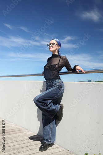 Young alternative woman with blue hair standing on wooden deck