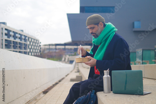 Konstfotografi Arab man with a beard and green scarf sitting on a concrete ledge
