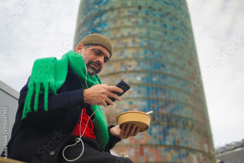 Bild auf Leinwand Arab man enjoying a lunch break outdoors, listening to music with earphones, che