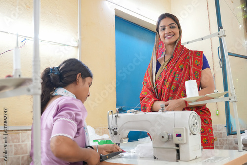 Two indian women are working on a sewing machine, creating garments in a fashion workshop, focusing on skill development and female empowerment. India