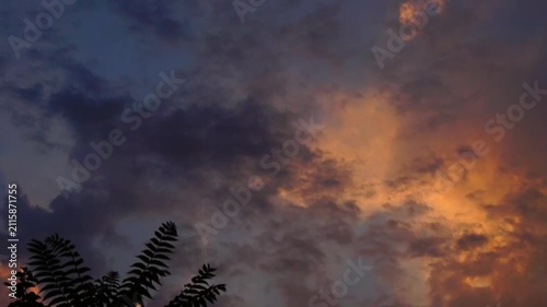 Time lapse video of dark clouds partially illuminated by sunset yellow solar sidelight across the sky from above to far