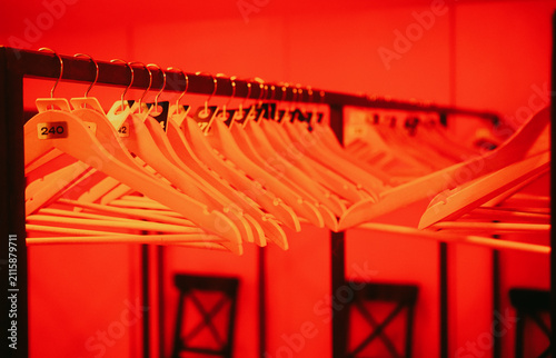 Bild auf Leinwand Wooden coat hangers with numbers in a cloakroom illuminated by intense red ambient light