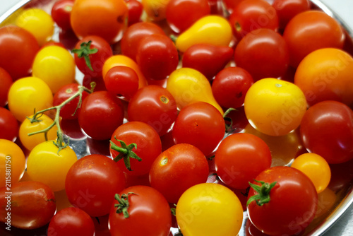 View of different types of cherry tomatoes on a silver tray, light background
