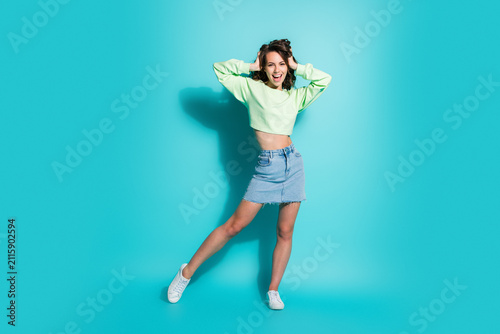 Fotografía Happy young woman in casual fashion posing on turquoise background with denim sk