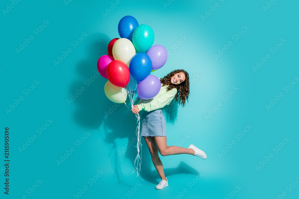 Obraz premium Happy young woman holding colorful balloons in a playful studio portrait celebrating a party moment