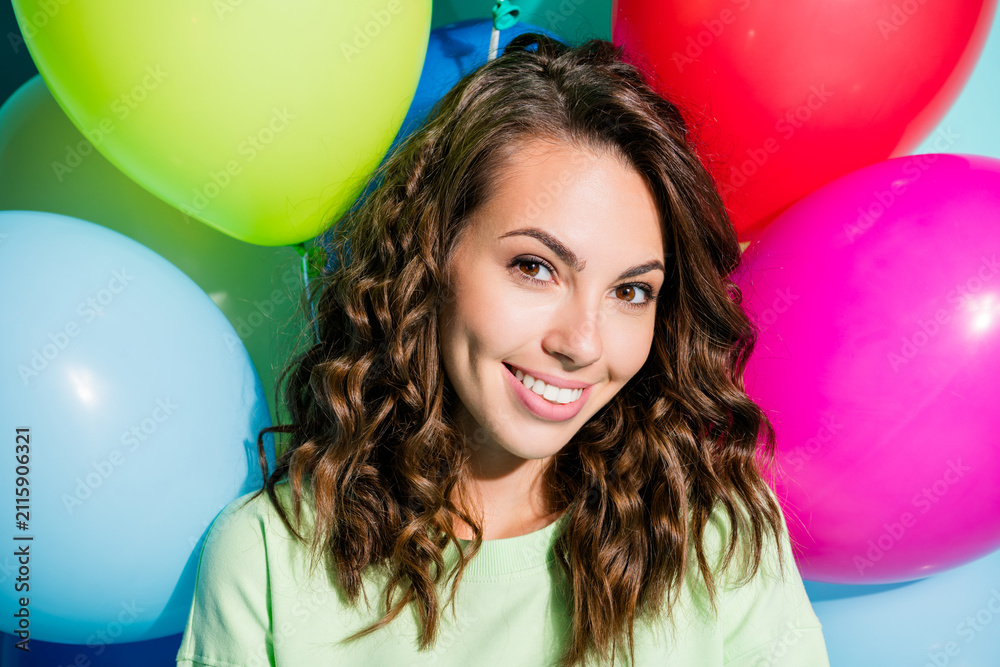 Obraz premium Smiling young woman with colorful balloons, curly hair and casual green top celebrating a cheerful party or birthday portrait conveying joy and positive lifestyle energy