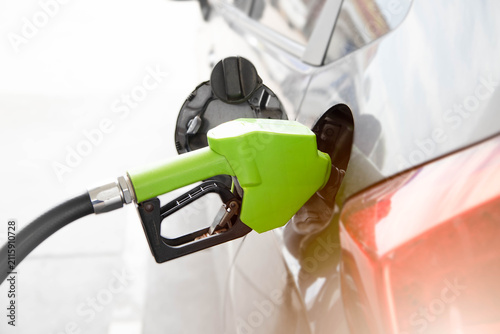 Konstfotografi Refueling car with gasoline at petrol station, fuel concept and transportation costGreen fuel nozzle refueling a car at a gas station close up