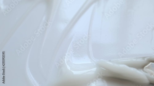 Macro shot of spatula spreading creamy white cosmetic product, creating beautiful texture