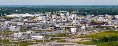 Aerial view of the industrial chemical plant complex with storage tanks, pipelines, and railroad tracks surrounded by green landscape in Midland, Michigan, United States.