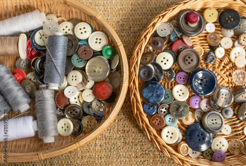 Foto Top view of wicker baskets filled with assorted sewing buttons and thread spools with a sewing needle