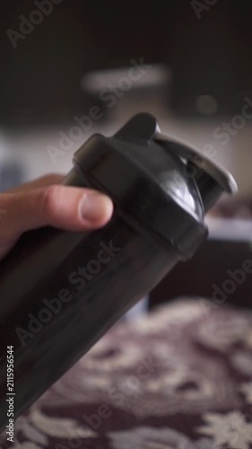 Close up POV of athlete shaking black plastic protein bottle mixing sports nutrition supplement