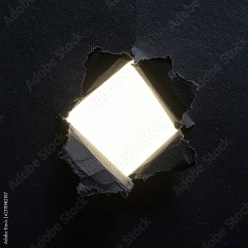 Jagged tear in dark paper reveals bright, square light source